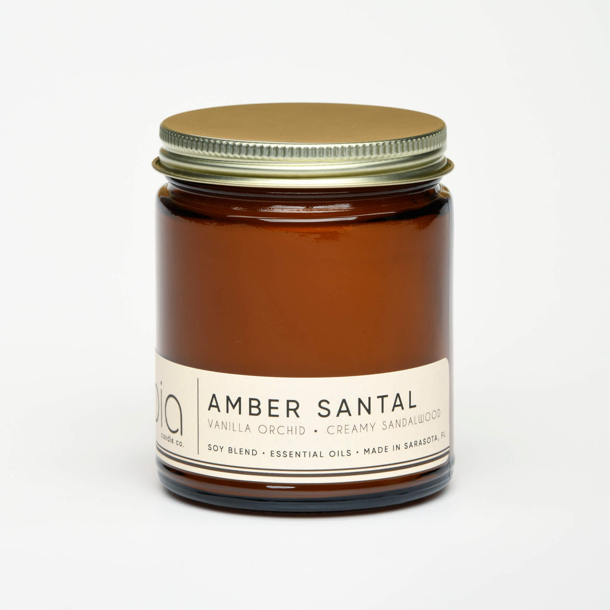 Amber glass soy candle jar with metal lid and printed label, unlit