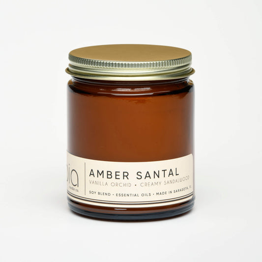 Amber glass soy candle jar with metal lid and printed label, unlit