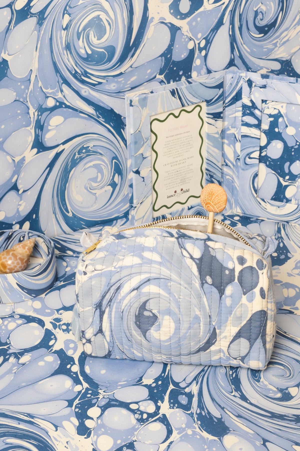 Close-up blue hand-marbled cosmetic bag with gold zipper and stitched label panel