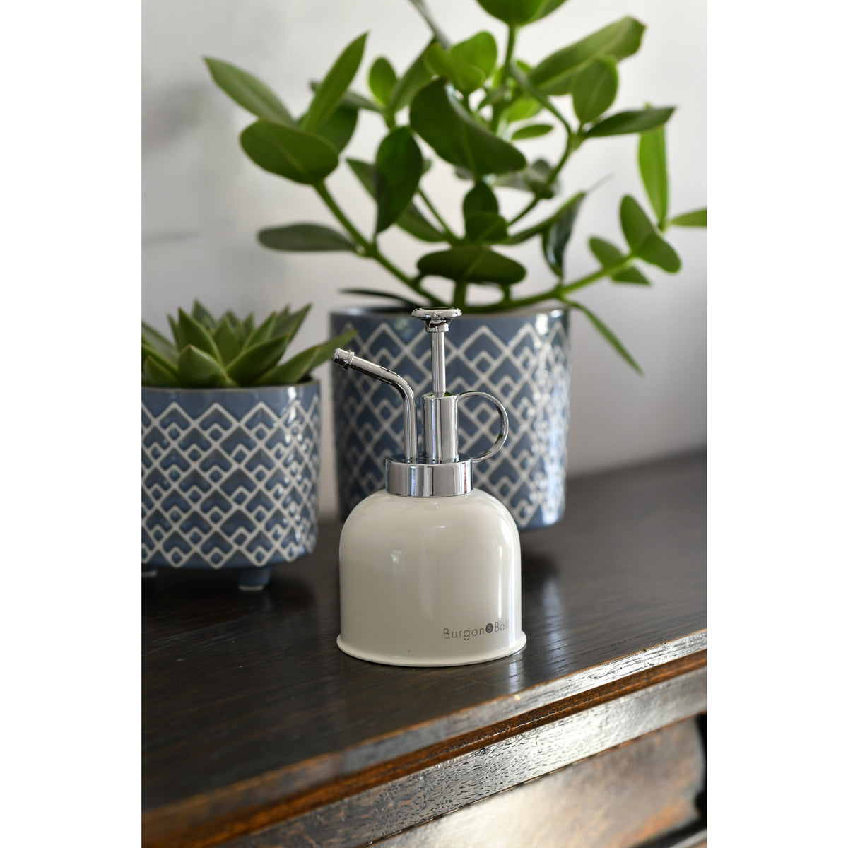 Stone-colored indoor plant mister on tabletop with chrome sprayer