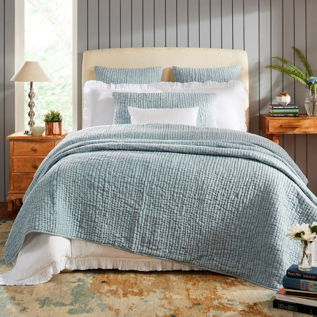 Blue-gray stone-washed cotton quilt with textured grid stitch, draped on bed.