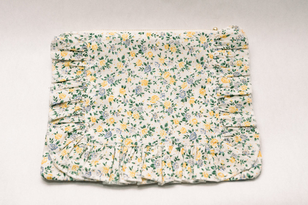 Cream floral zipper pouch with ruched ruffle trim and gold zipper pull at top.