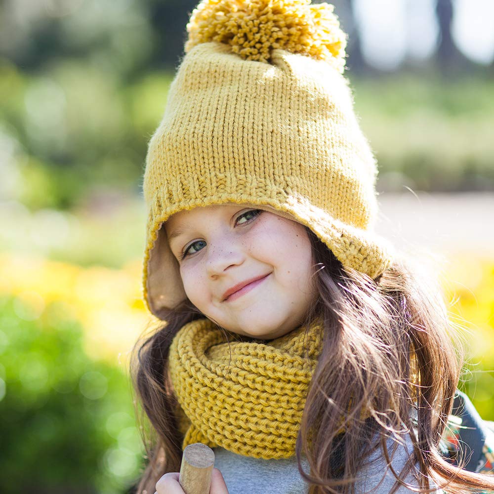 Child wearing a mustard knitted earflap hat with pom-pom