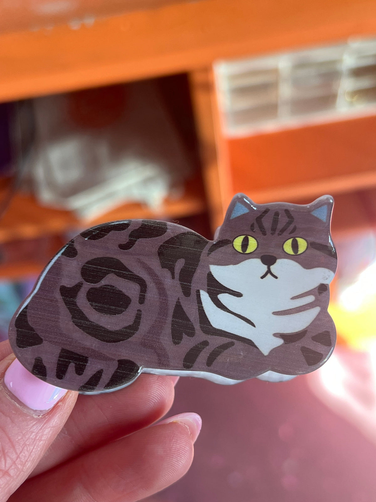 Oopsy Daisy hair claw, cat design with black-and-gray fur and green eyes.