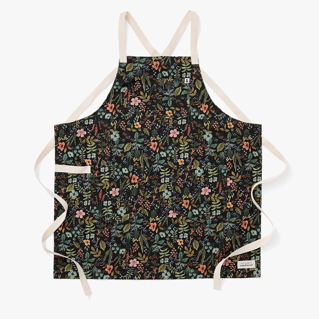 Black floral crossback apron with beige straps and multicolor flowers