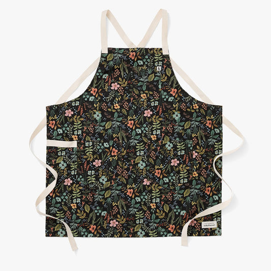 Black floral crossback apron with beige straps and multicolor flowers