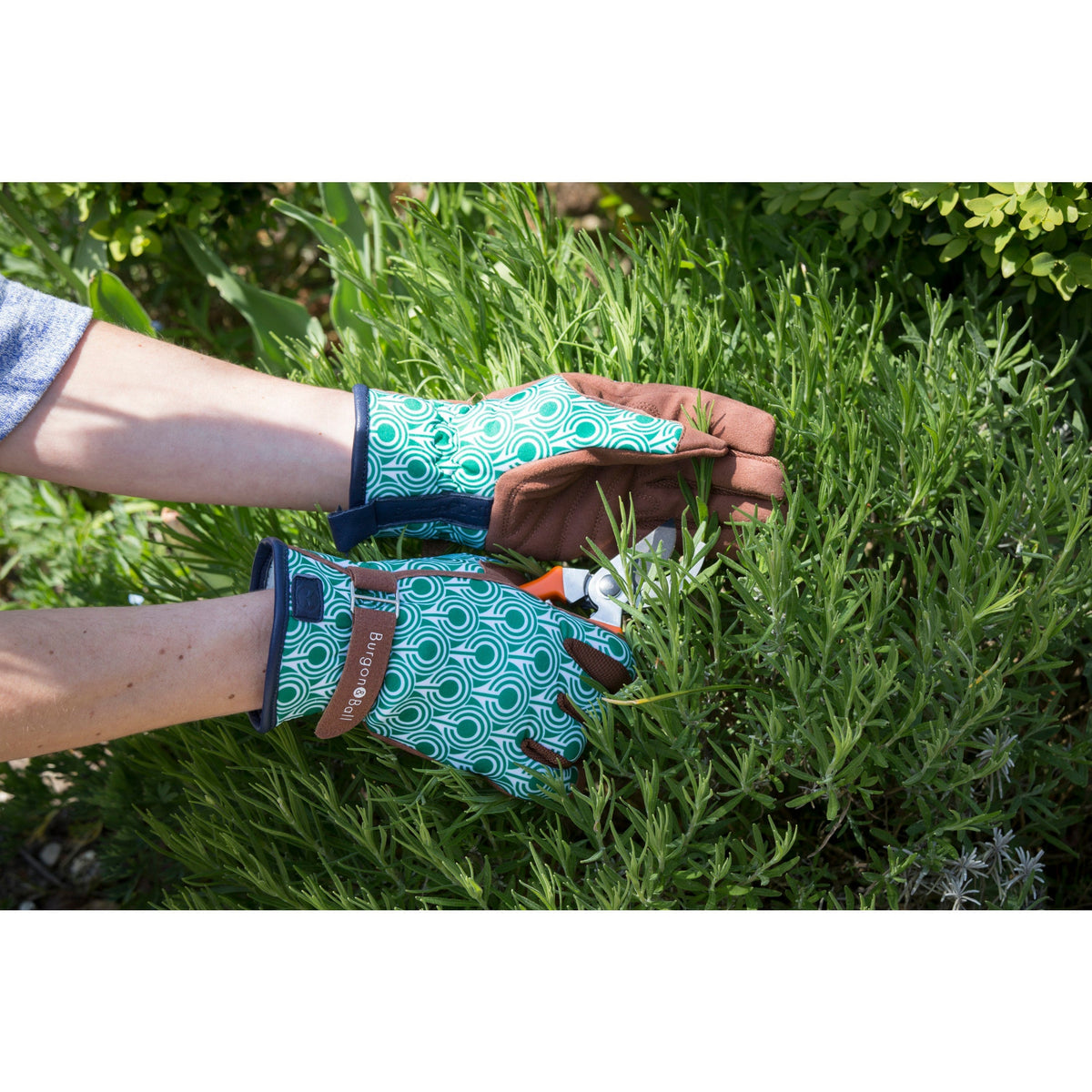 Garden glove pair on hands outdoors, teal geometric print with brown wrist closure