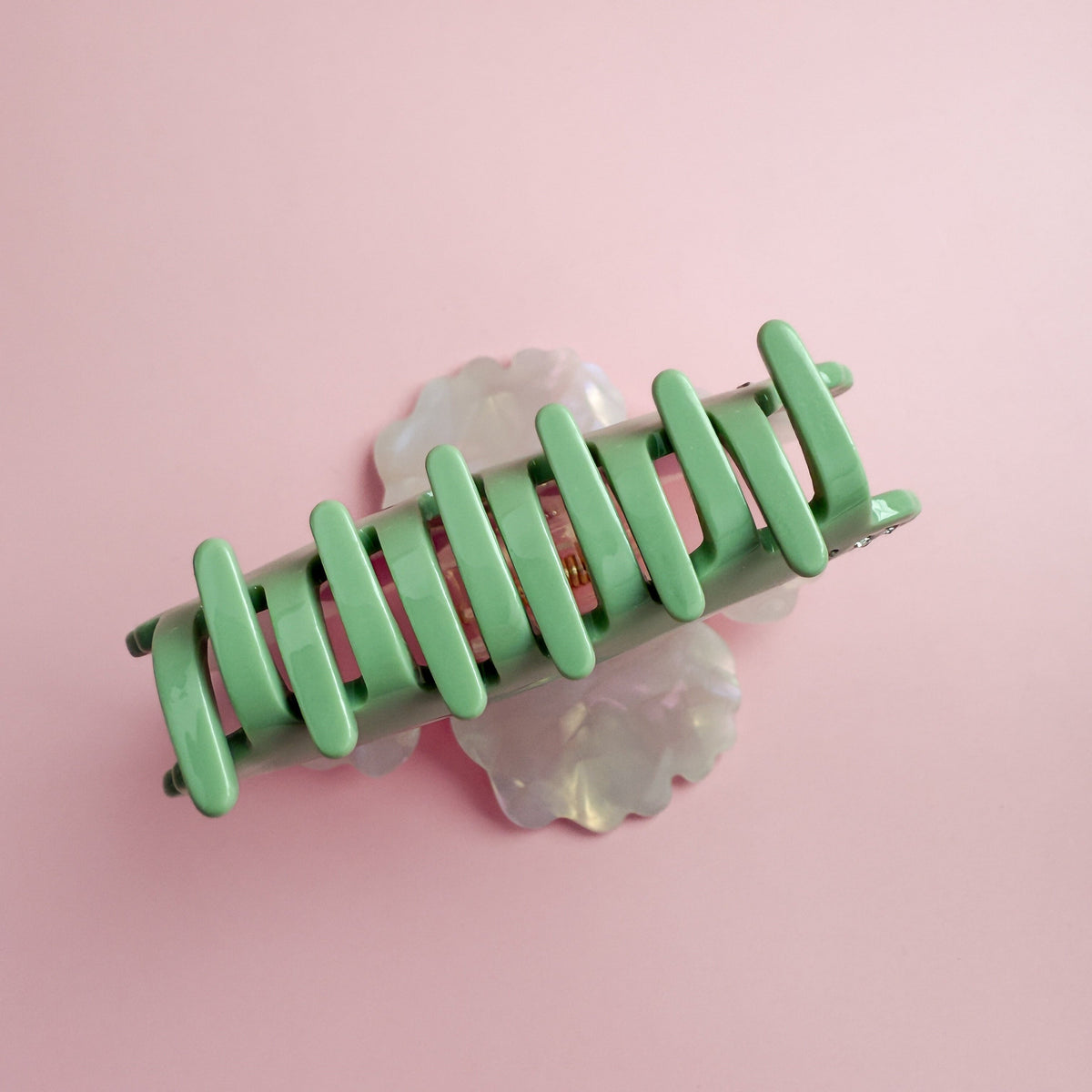 Translucent opalescent hair claw with green comb-like teeth and floral back