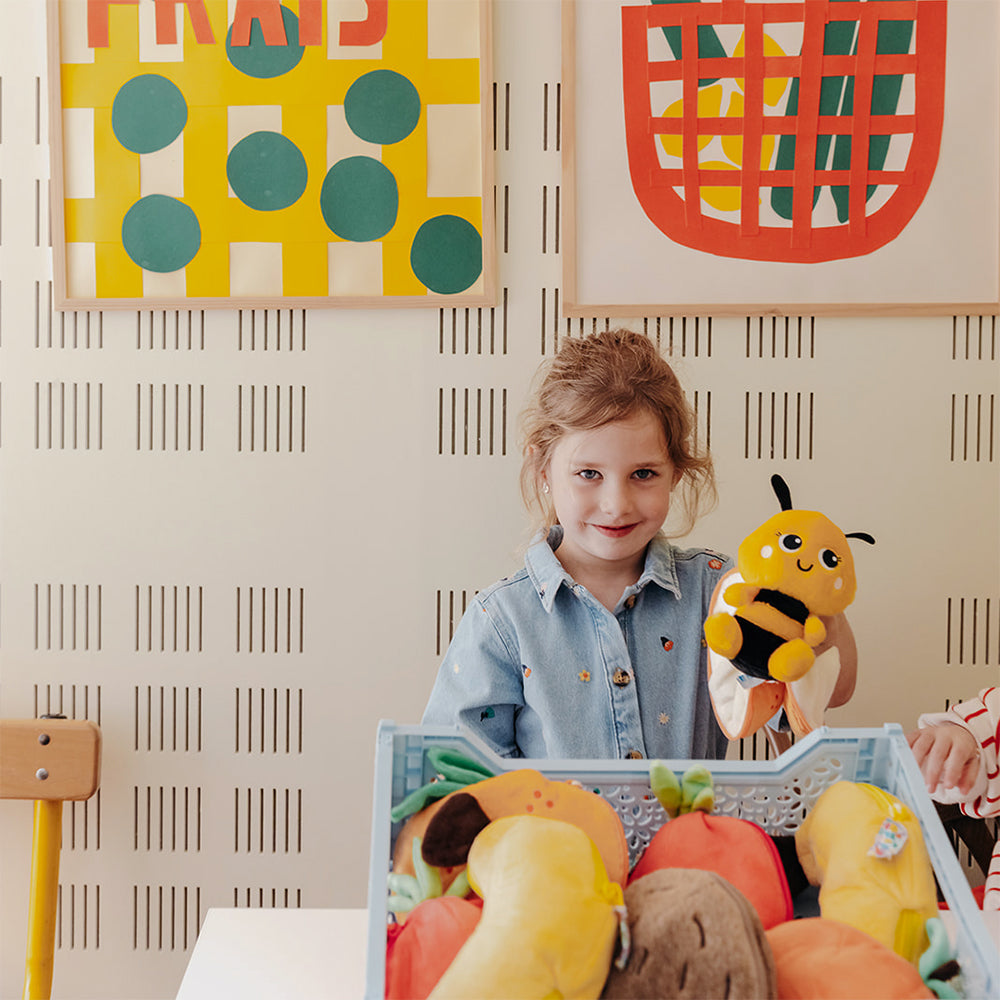 Plush bee and tangerine toys in a gift box, shown with a child holding one.
