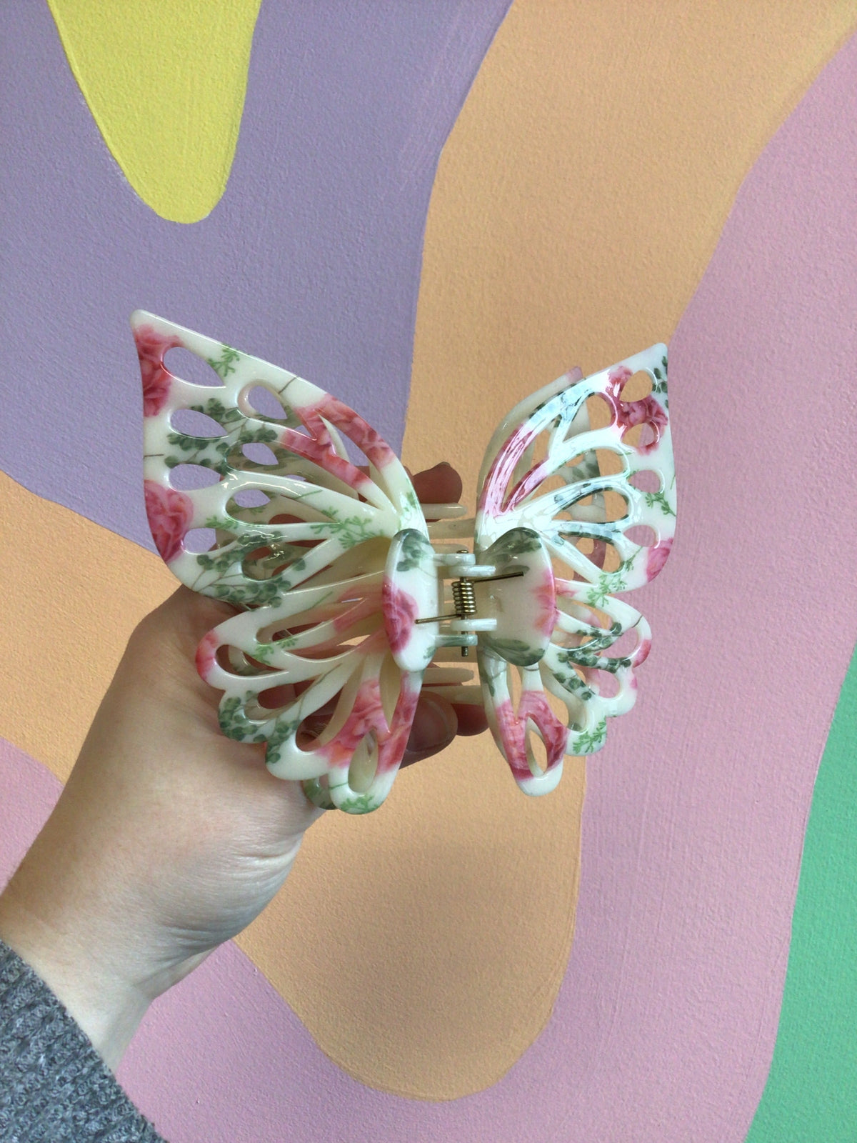 Pink and green butterfly hair claw clip with curved metal teeth