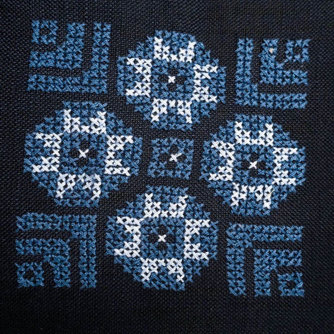 Dark blue pillow cover close-up with blue and white cross-stitch geometric pattern