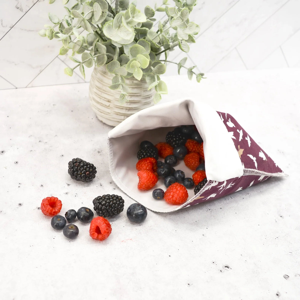 Reusable snack bag with berry print, open top with zipper-style closure and pouch shape