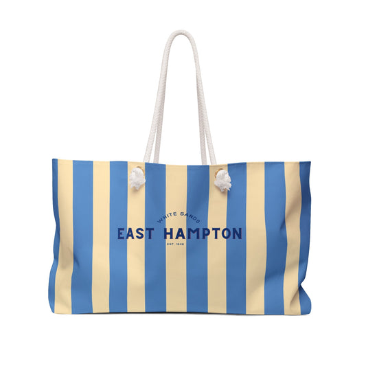 Blue and beige striped weekender tote bag with white rope handles and charm accents