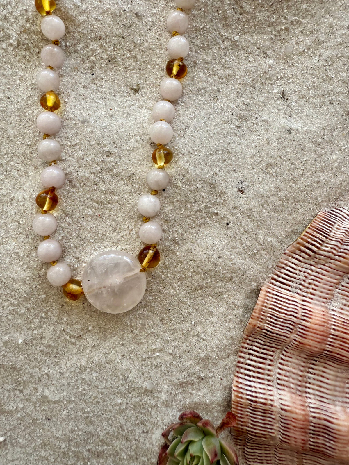 Stone bead necklace with pink beads, gold amber beads, and oval heart rose quartz pendant