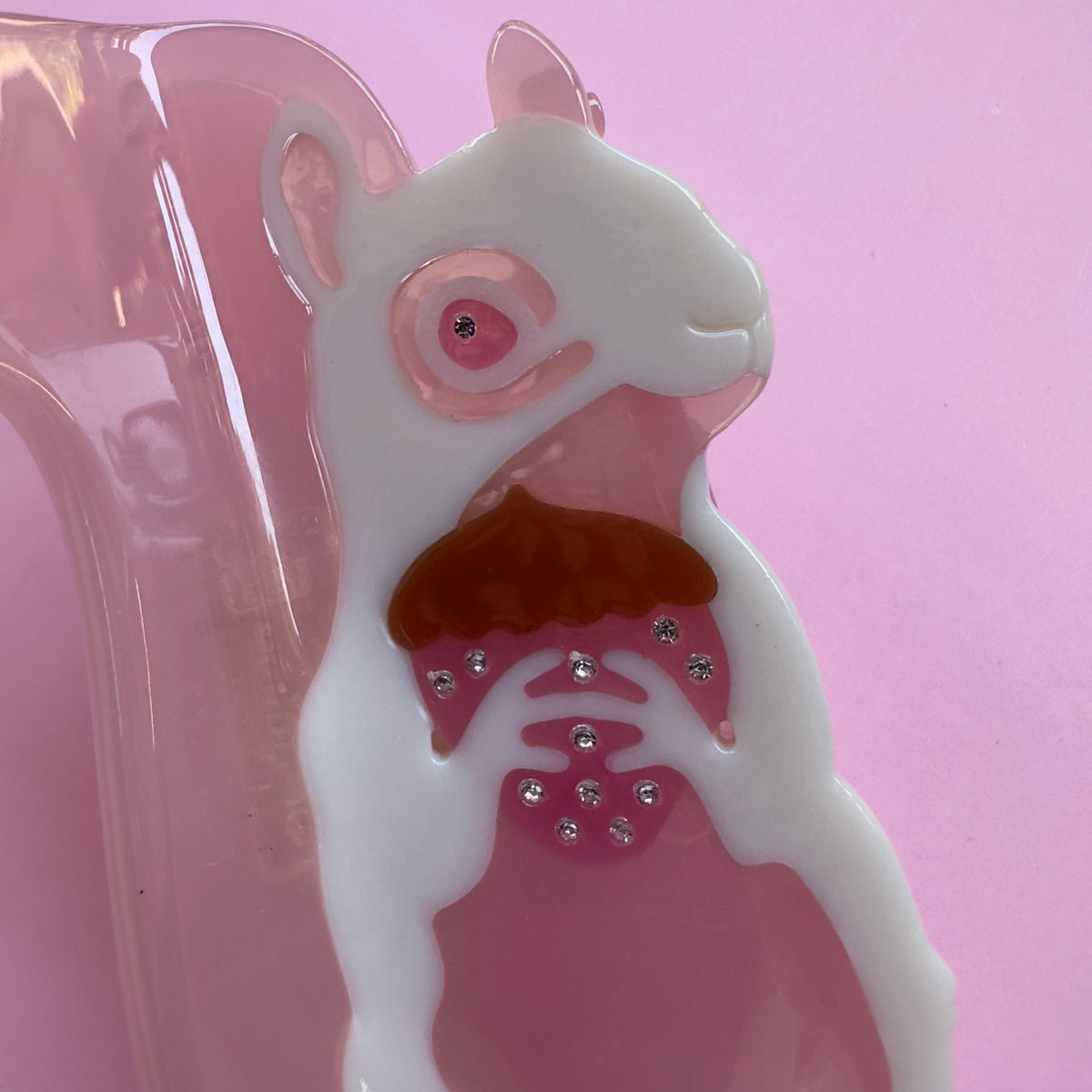 Close-up squirrel hair claw with white face, pink belly, and rhinestone details