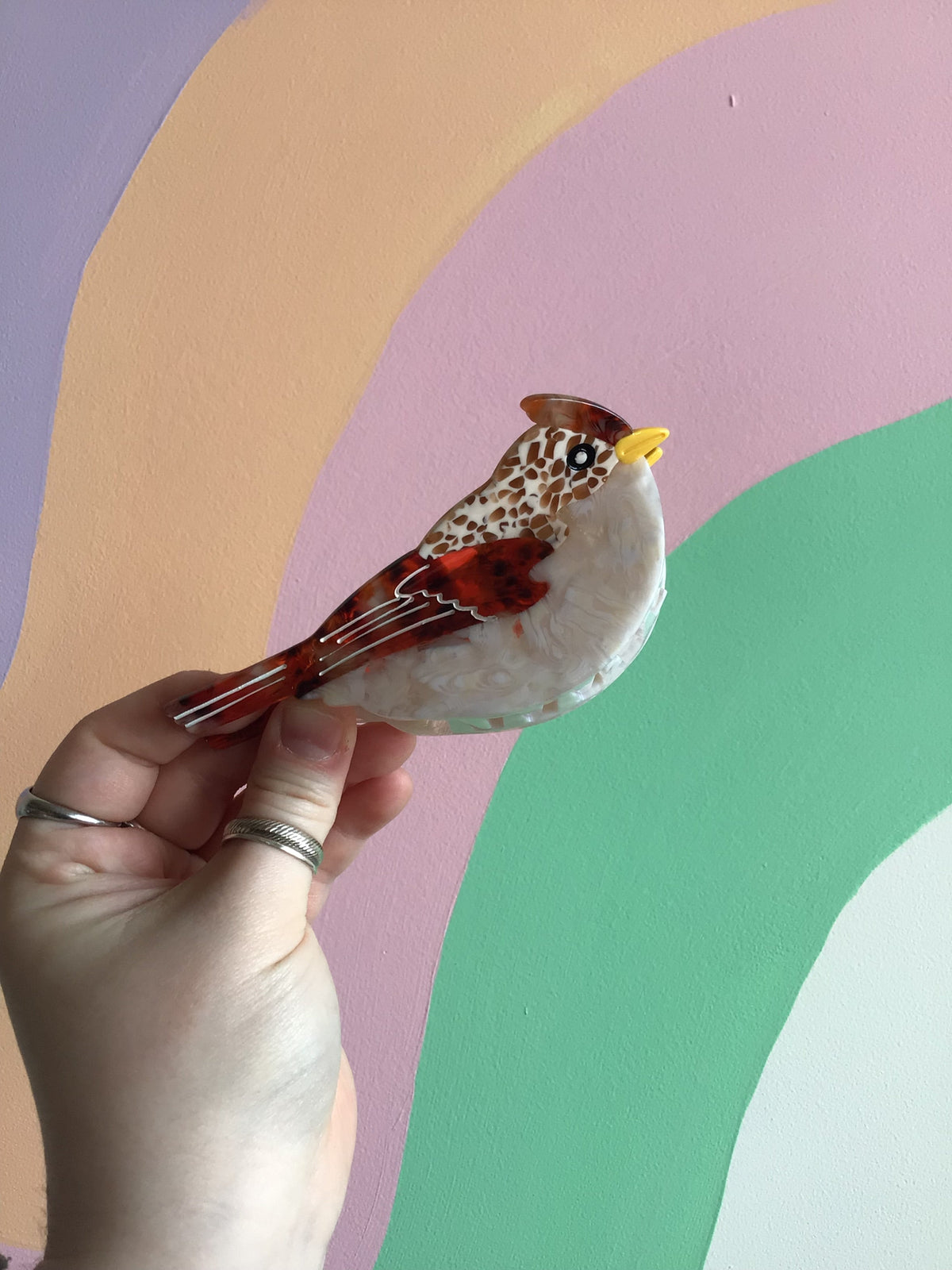 Red and brown bird hair claw with cream body and feather-pattern wings