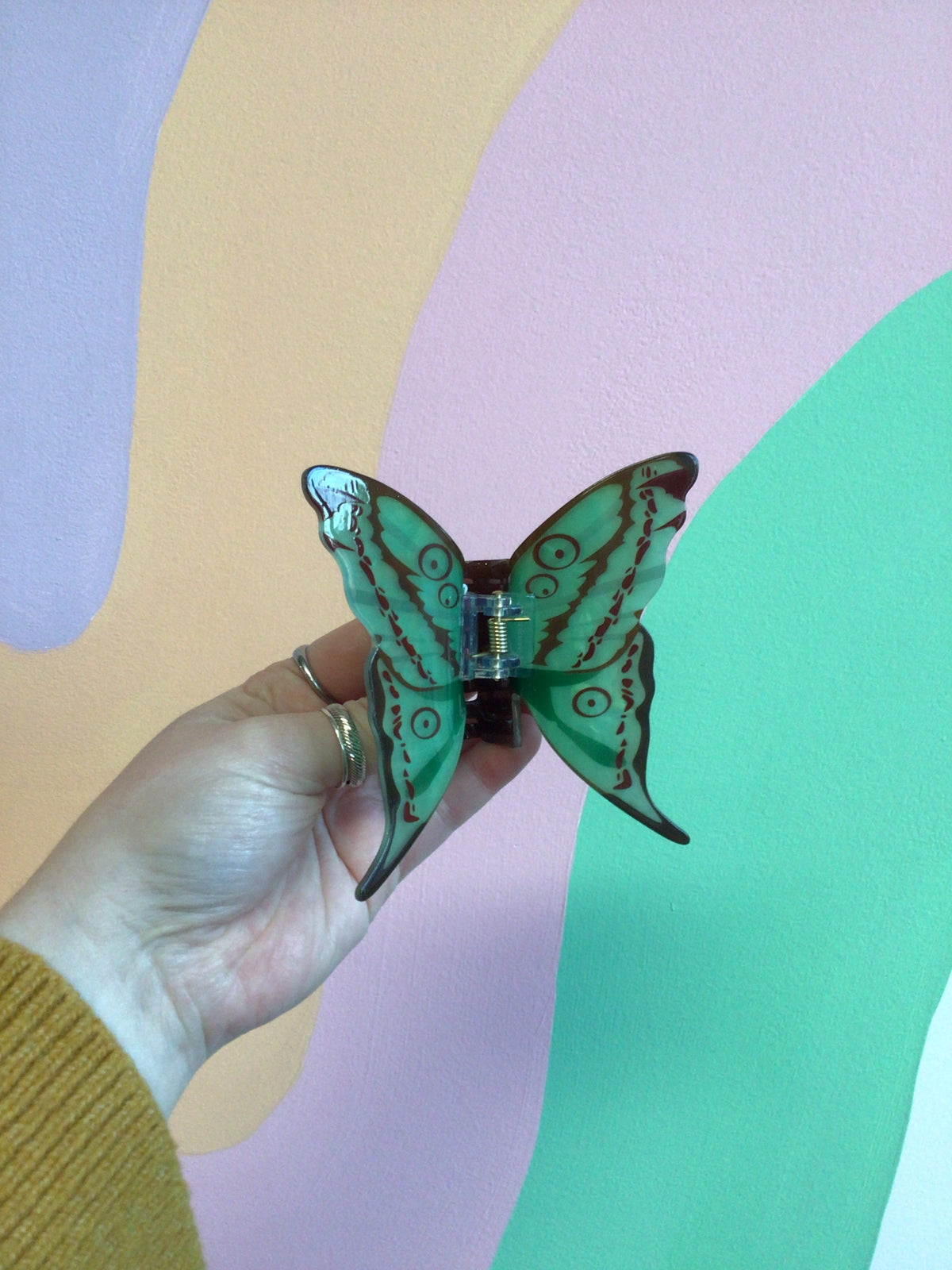 Teal butterfly hair claw clip with dark details and central hinge.