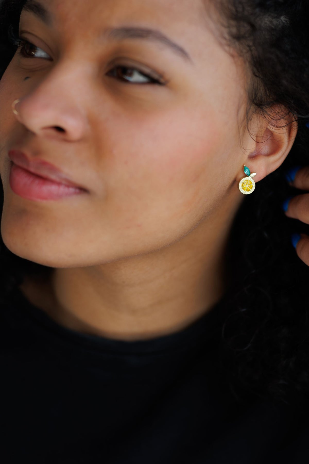 Lemon stud earring on model: gold textured round charm with teal top and green leaf