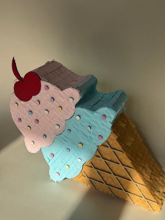 Handcrafted ice cream cone piñata with pink, blue, and brown scoops and polka-dot sprinkles