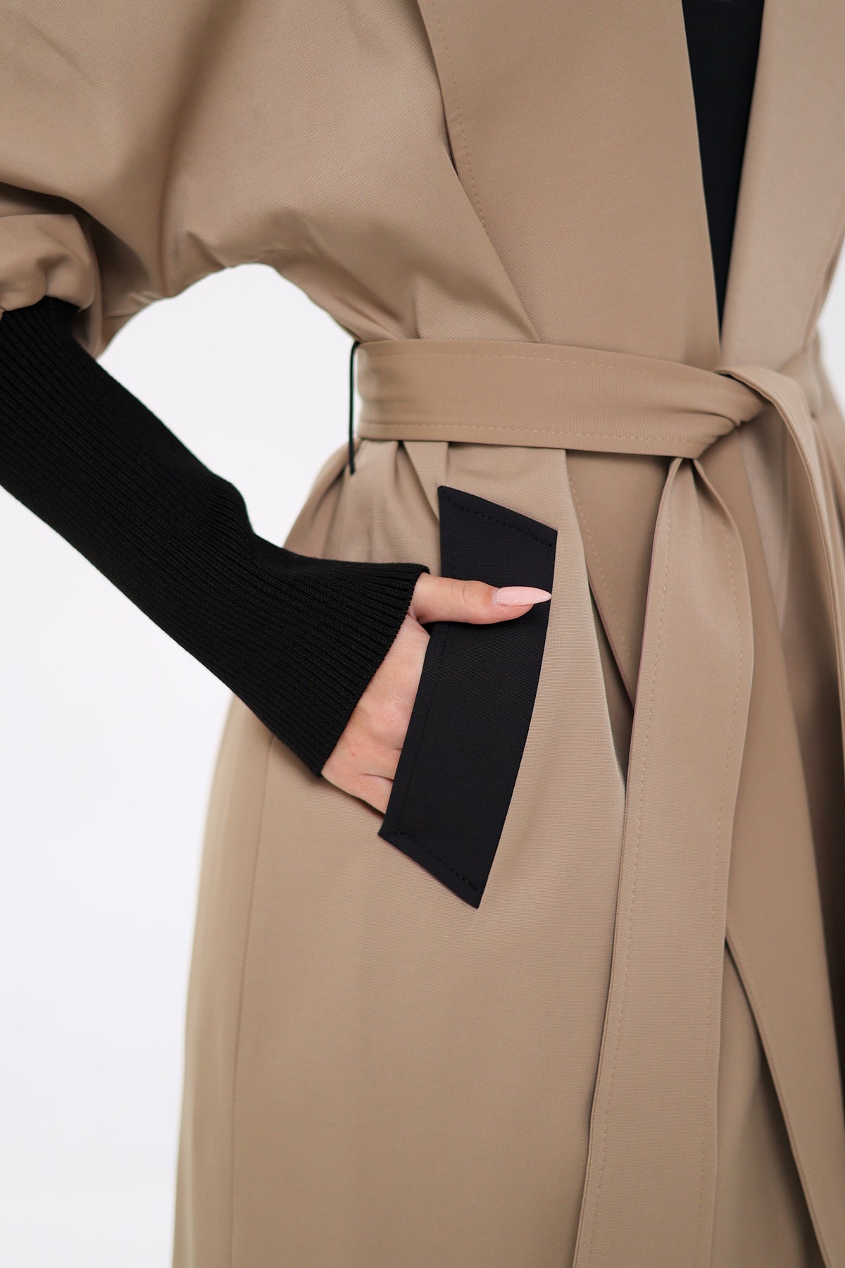 Miru trench coat detail showing a black-trimmed pocket and waist belt