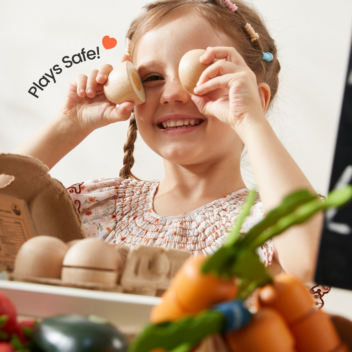 Smiling child holding wooden toy food pieces during pretend play