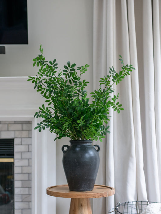 Artificial boxwood stems bundle of 4 in dark ceramic vase on round wooden stand