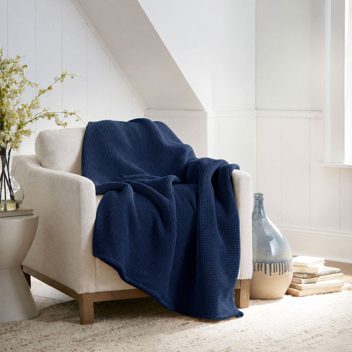Dark navy waffle-knit blanket draped over sofa arm, textured weave.