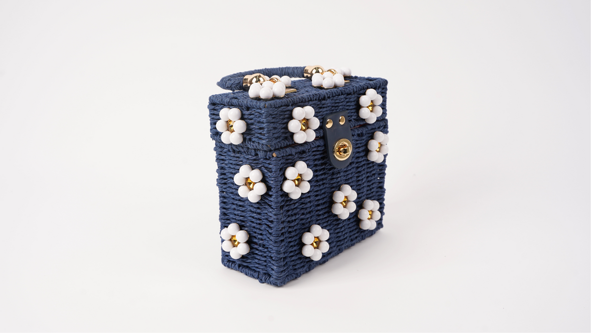 Navy woven mini tote bag angled view with white flower details and gold hardware