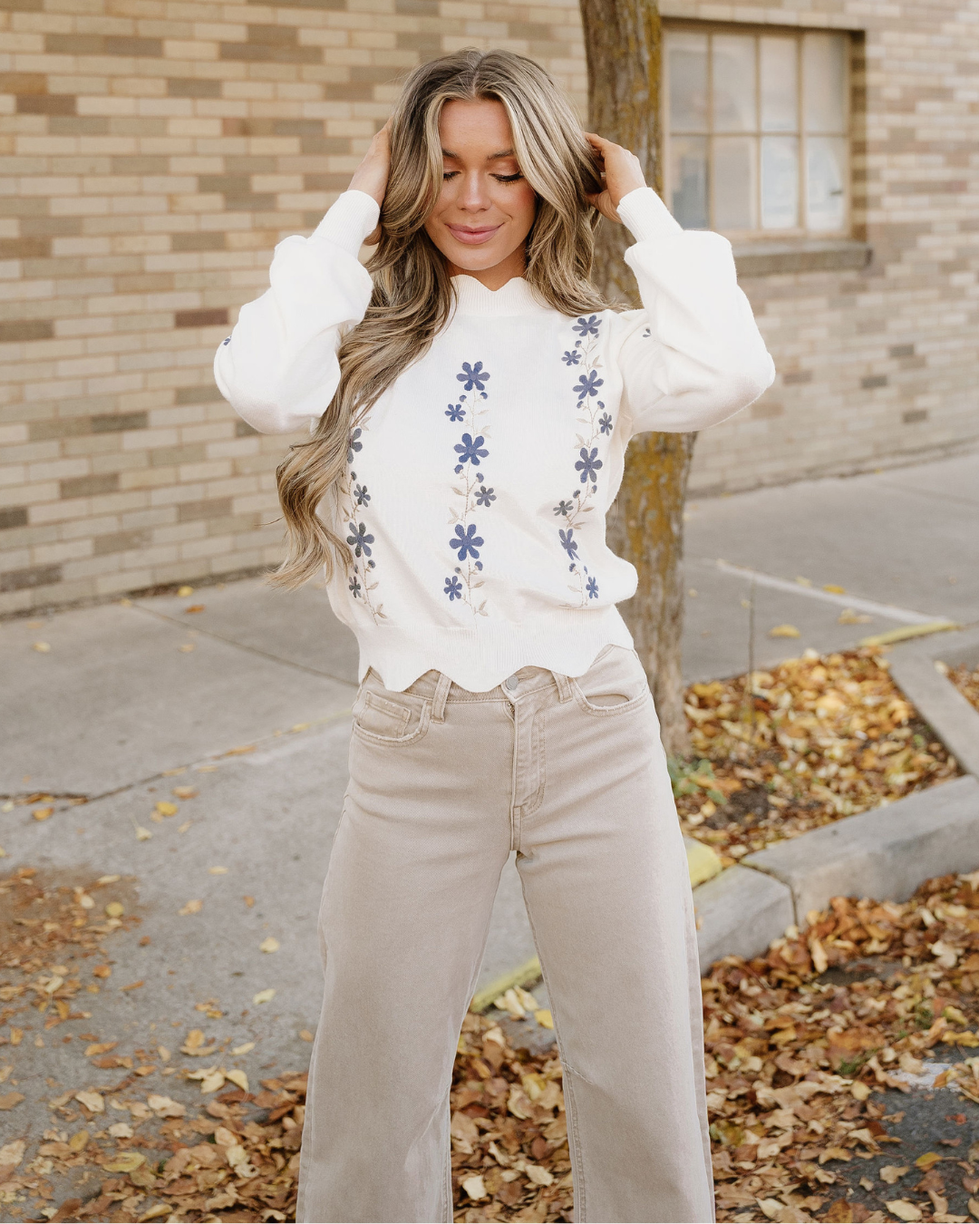 White cropped sweater with blue floral embroidery and ribbed cuffs