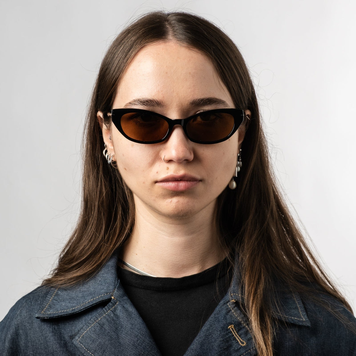 Person wearing black polarized sunglasses with bronze lenses, front view on face.