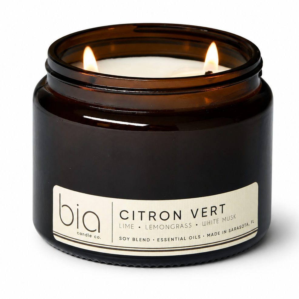 Dark amber soy blend candle jar with lit wick and cream Citron Vert label.
