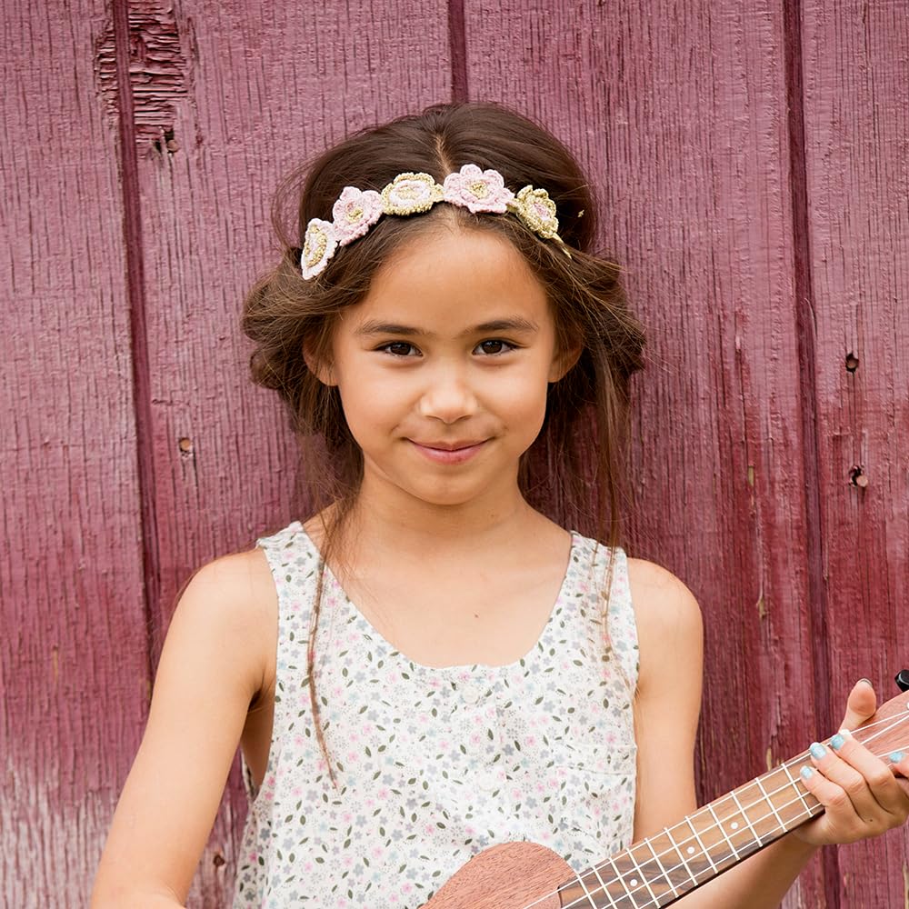 Pink and gold knitted flower headband worn across a child's hair