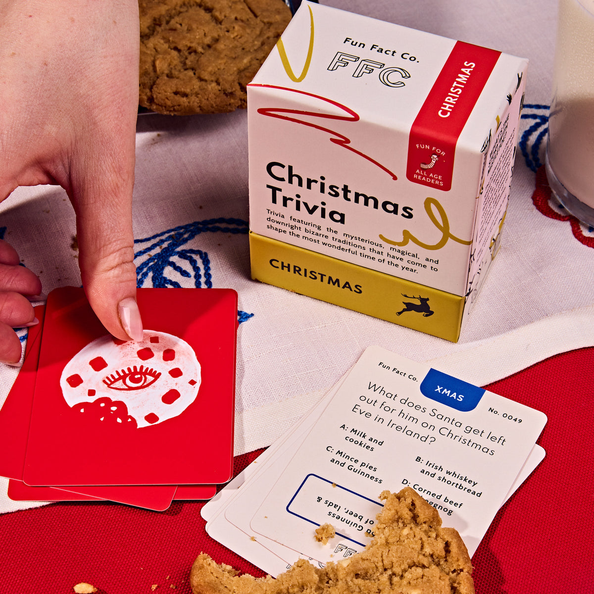 Christmas trivia card game with box and red cards as a hand places one