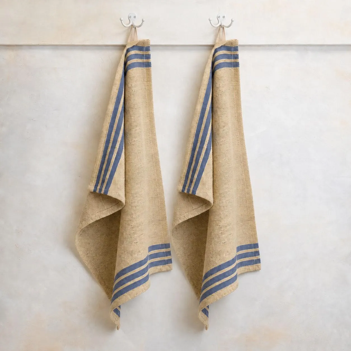Handwoven cotton kitchen towels hanging on hooks with blue striped border