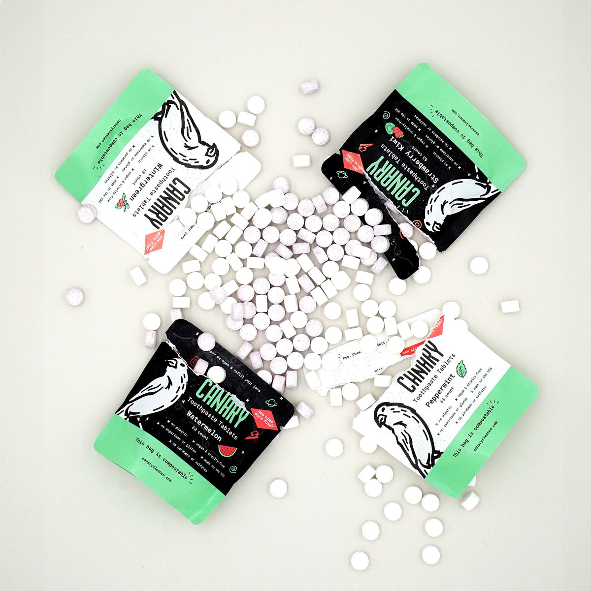 Canary toothpaste tablet sampler with four green-and-white pouches and loose tablets
