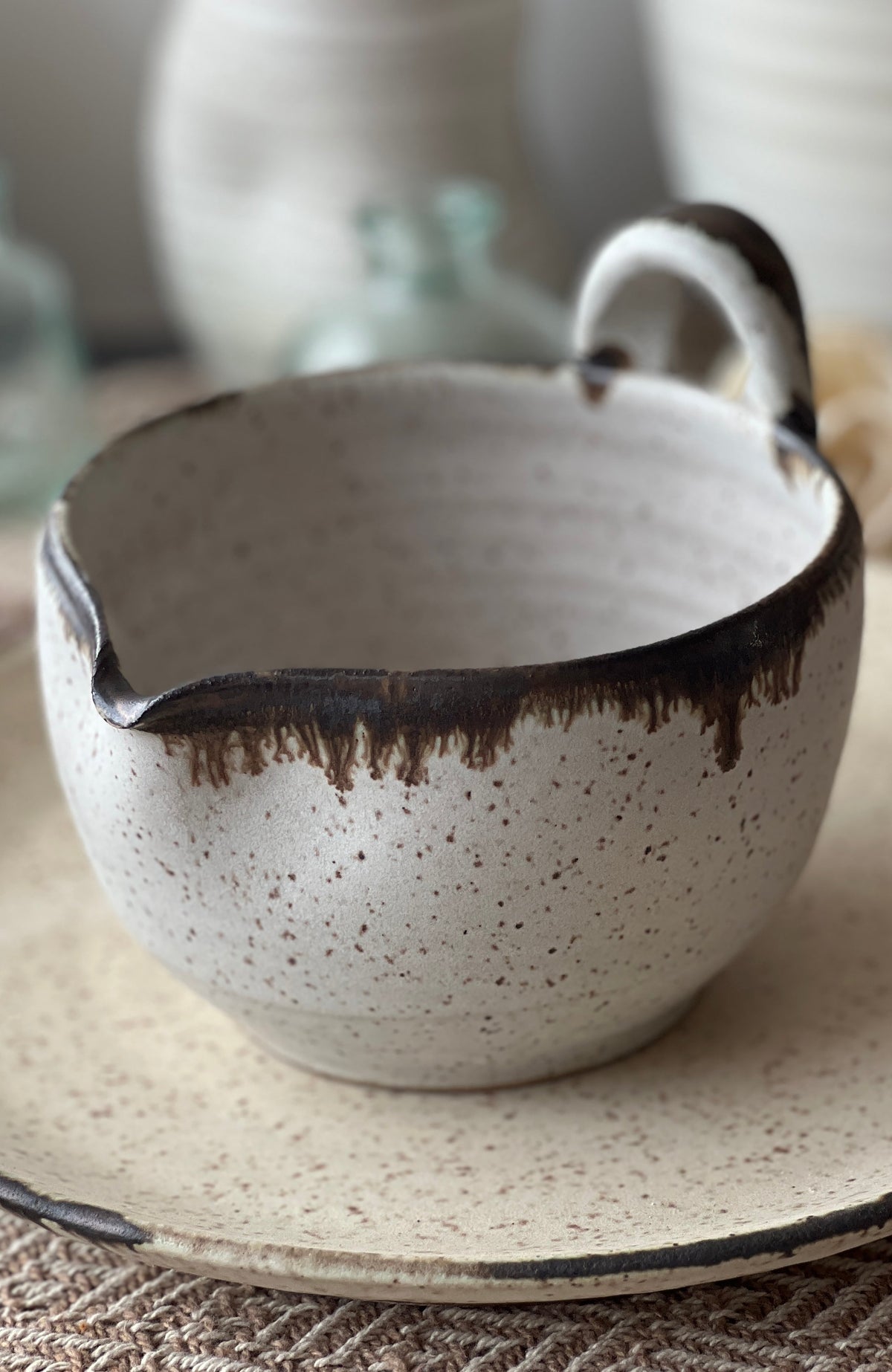 Speckled beige batter bowl with dark drip glaze and side loop handle