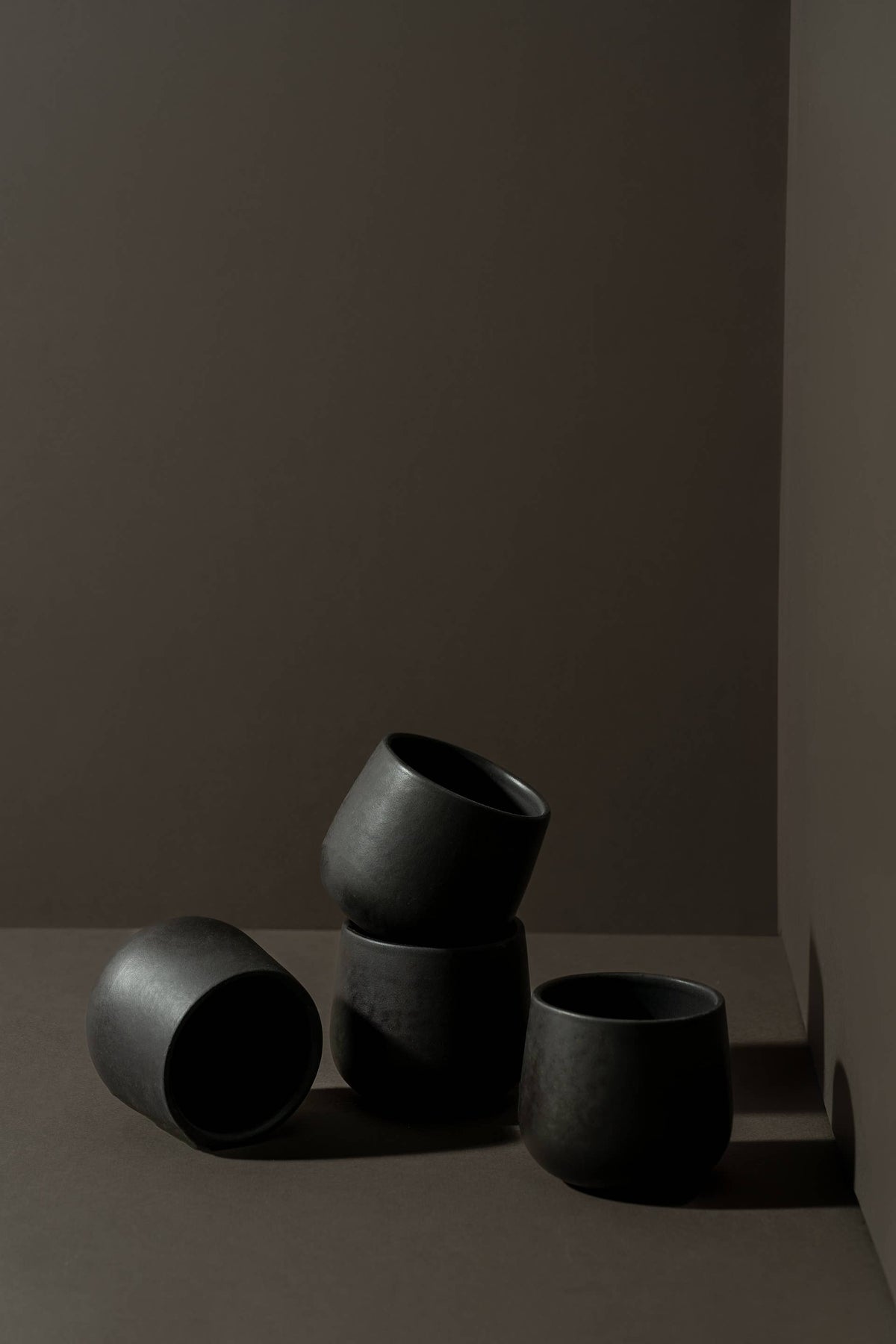 Matte black stoneware coffee cups, three small mugs grouped in a corner