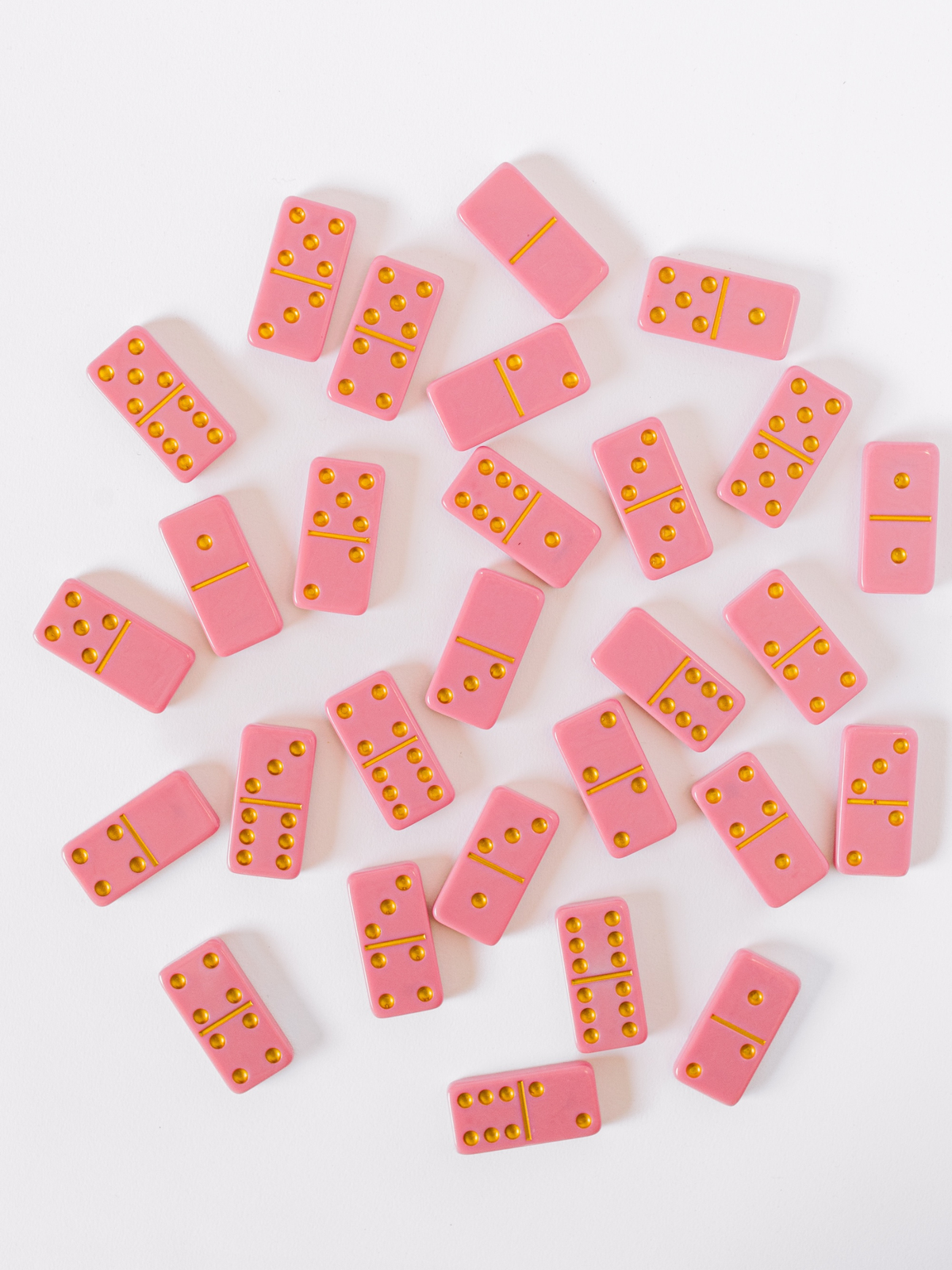 Close view of scattered pink marbled domino tiles with yellow dot pips