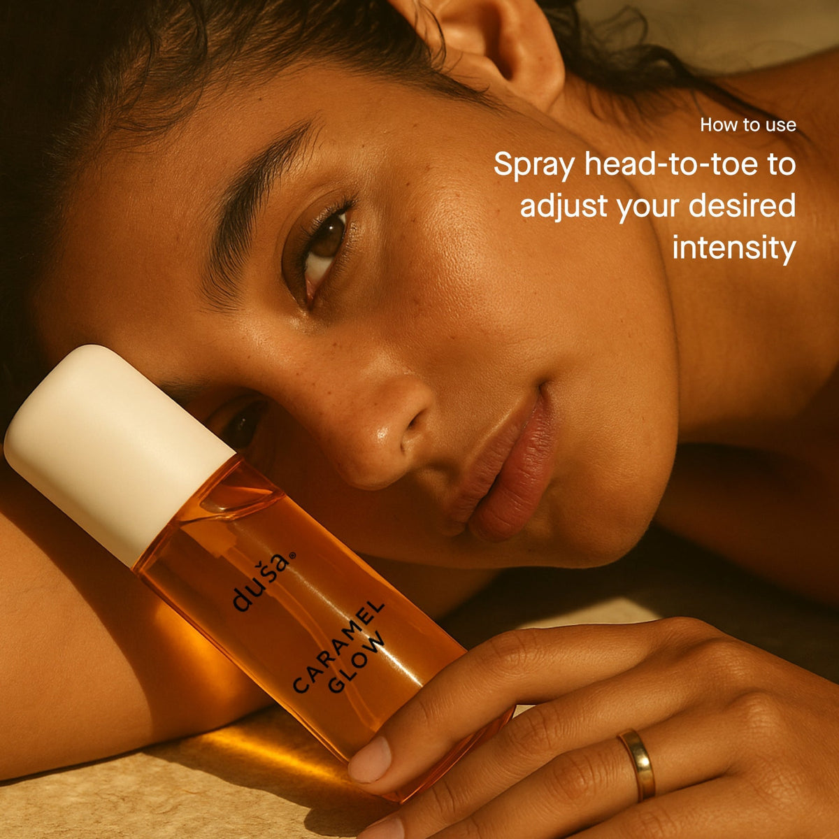 Caramel Glow perfume mist bottle with white cap held in a hand