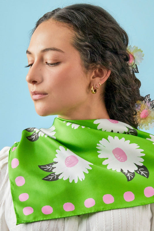 Green silk scarf draped over shoulder with white and pink floral design and pink dots