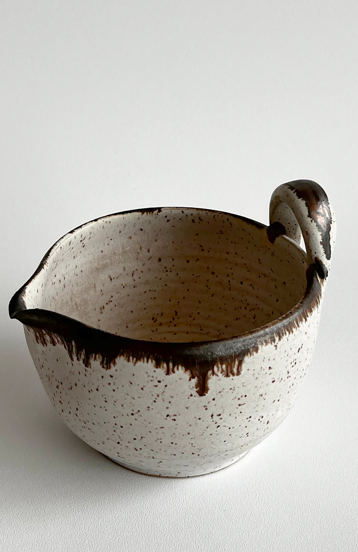 Speckled white batter bowl with dark rim and loop side handle