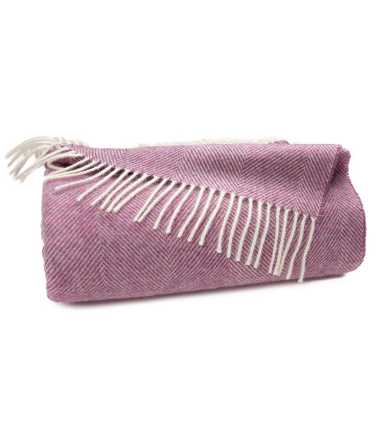 Petal pink herringbone throw blanket with cream tassel fringe along one edge