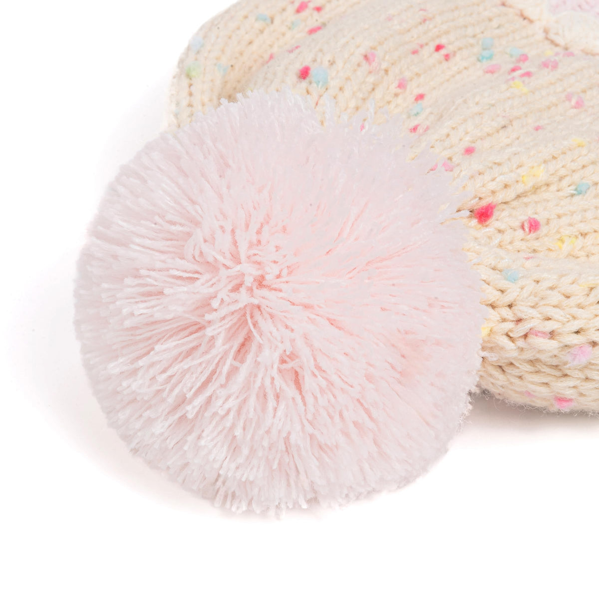 Close-up of pale pink pom-pom on a cream sprinkle-knit children's beanie