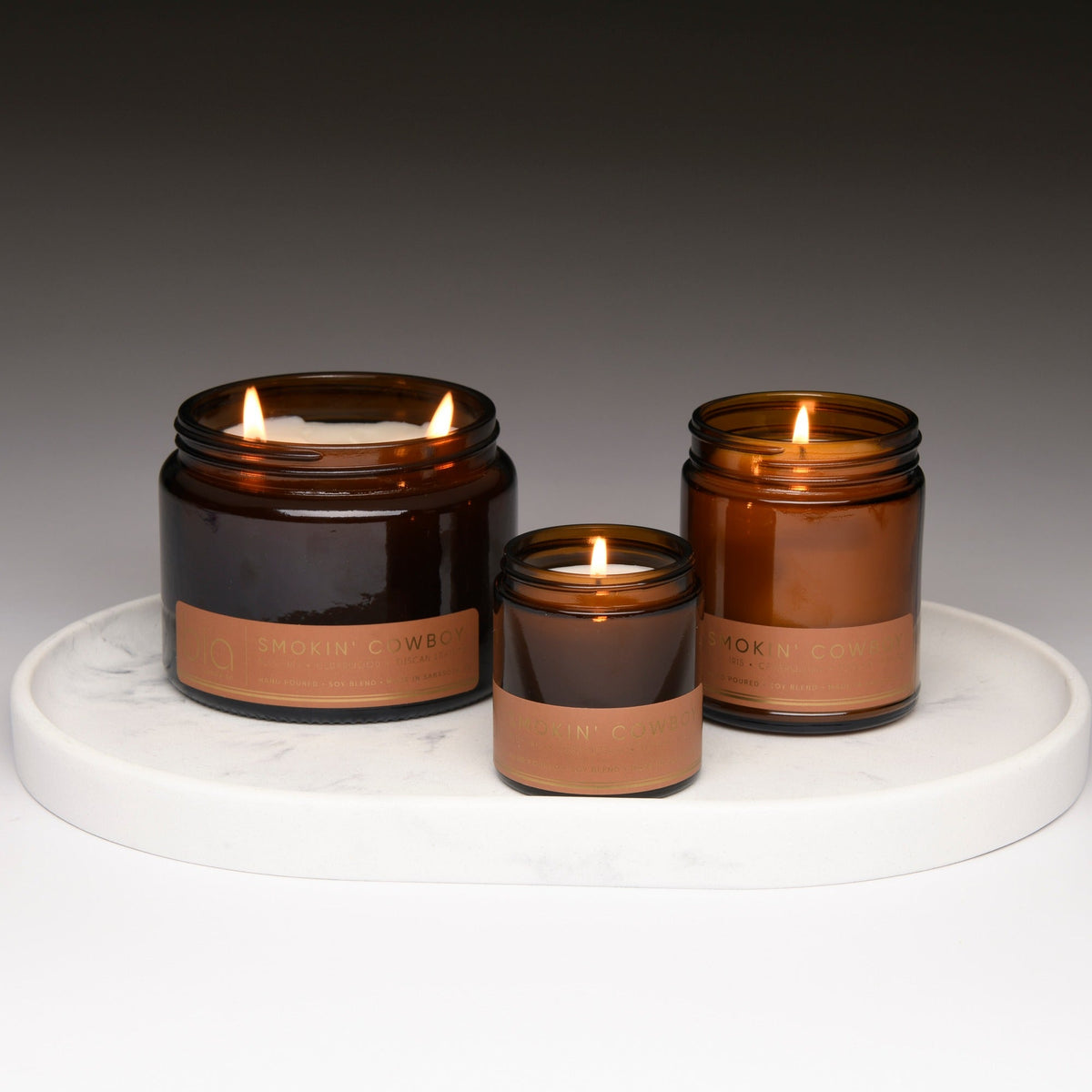 Set of three amber soy candles with lit flames on a round tray