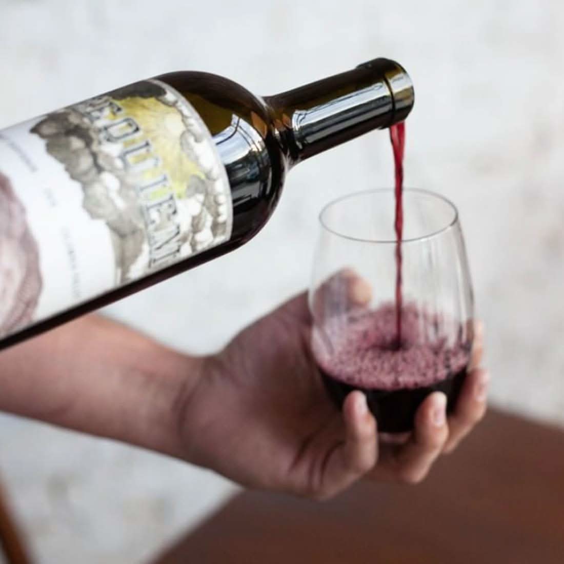 Clear 12 oz stemless wine glass as red wine pours from a bottle