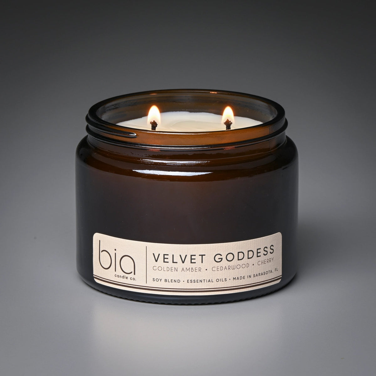 Brown glass candle jar with two flames and front label branding