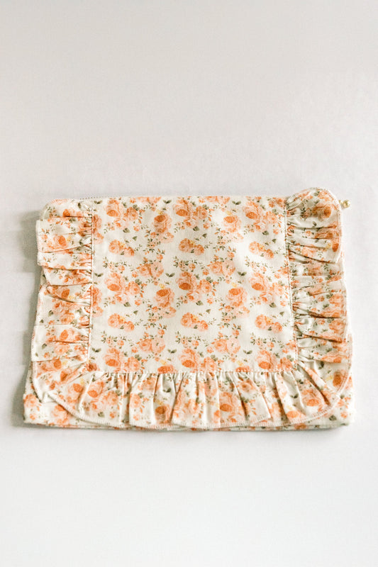 Floral ruffle zipper pouch with coral orange blooms on light fabric and gathered bottom