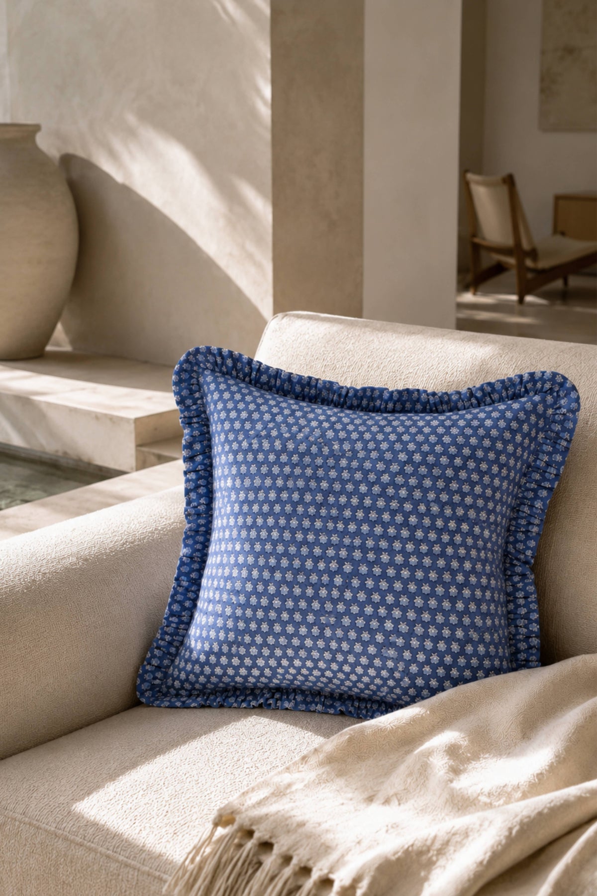 Blue blockprint pillow cover with ruffled border on a sofa cushion
