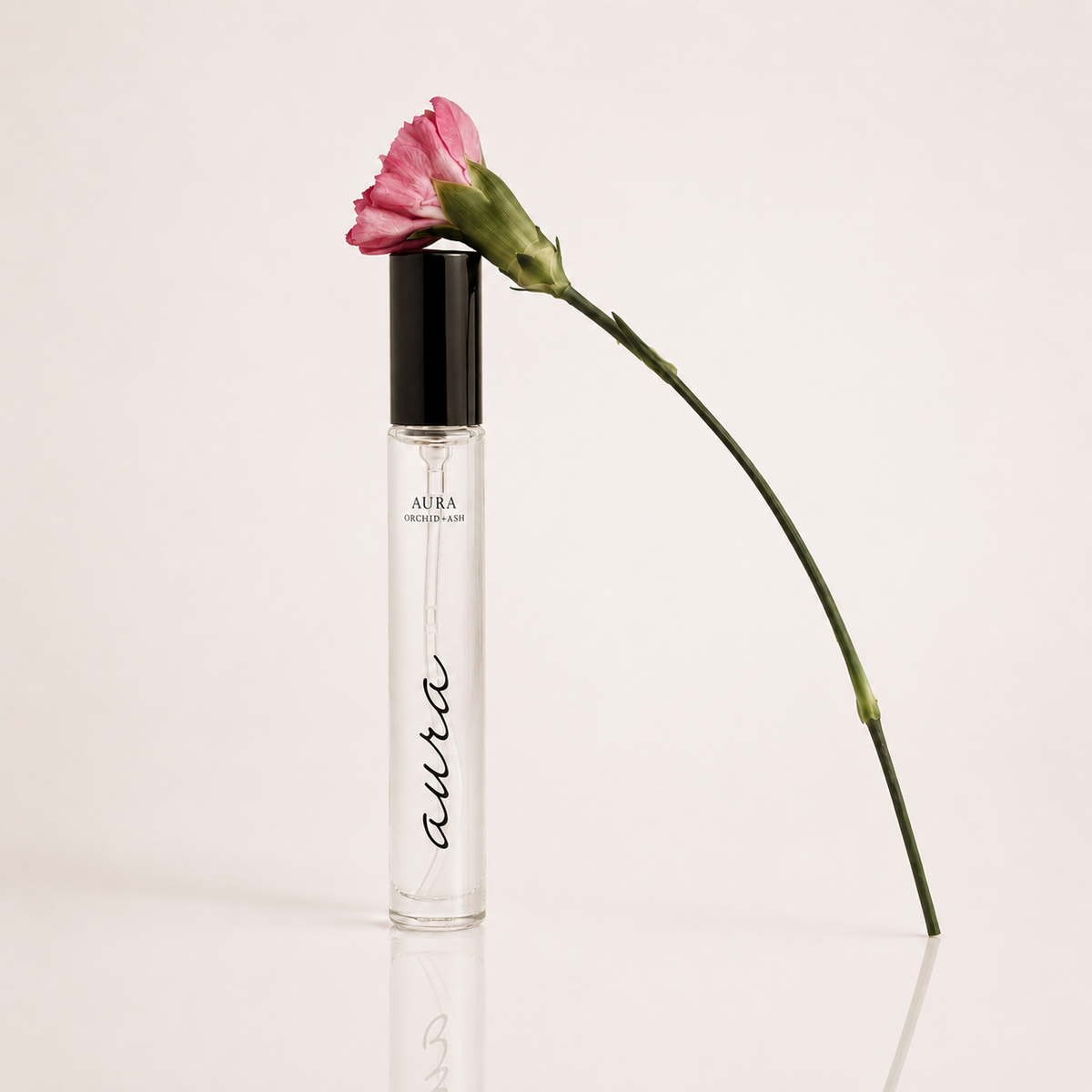 AURA perfume travel spray bottle with clear liquid, black cap, and pink flower on stem