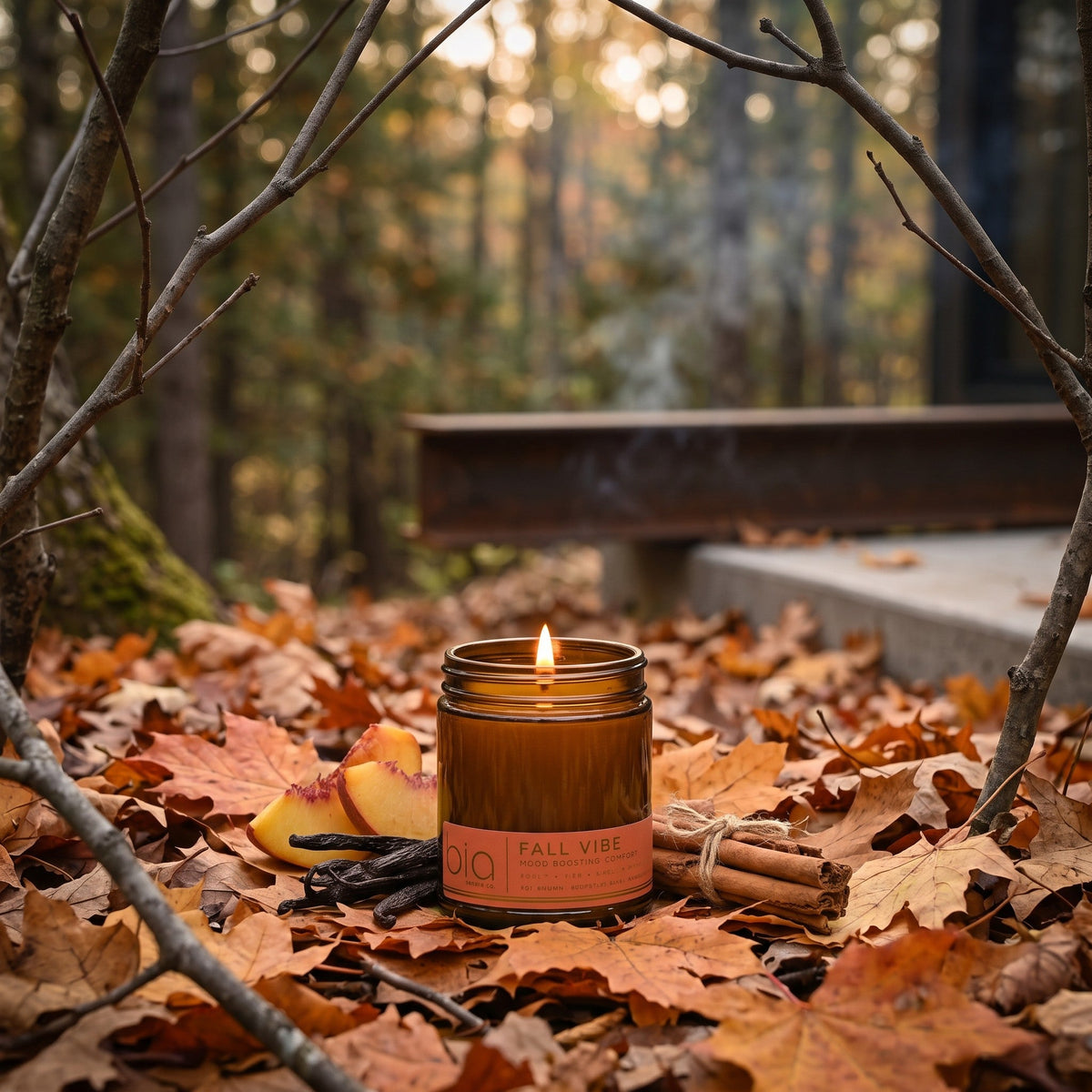 Amber soy blend candle jar with lit wick and 'bio' Fall Vibe label among fallen leaves